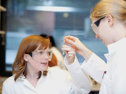 Two women analysing the content of a test tube