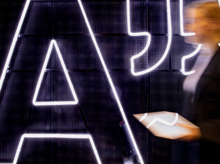 A woman walking by a large Aalto logo sign