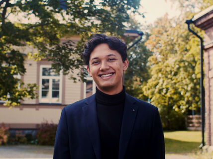 2nd year student of the BScBA Programme Johan Salim is standing outside in sunny weather with a big smile on his face.