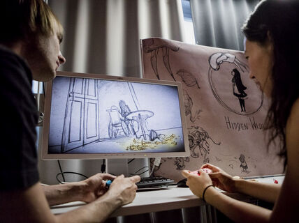 Two people discussing about a scetch they are looking on a computer