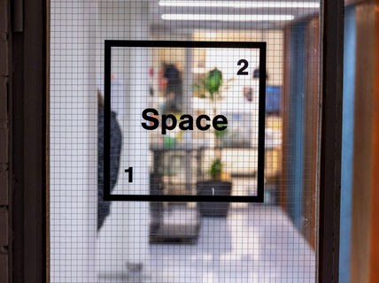 Space 21 logo taped on the glass door with the place itself visible through it.