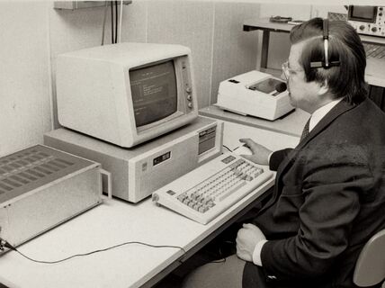 Mustavalkoisessa arkistokuvassa Teuvo Kohonen istuu vanhanaikaisen tietokoneen äärellä.