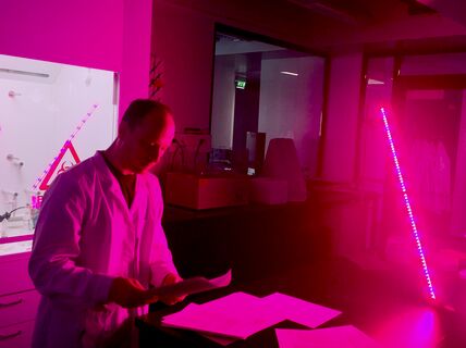 James Evans reading scientific paper in a chemistry lab in purple glowing light
