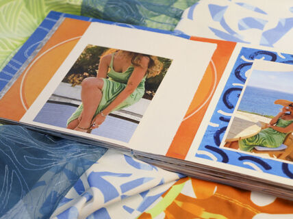 An illustrated book with model wearing summery outfit lays on colourful textiles surface