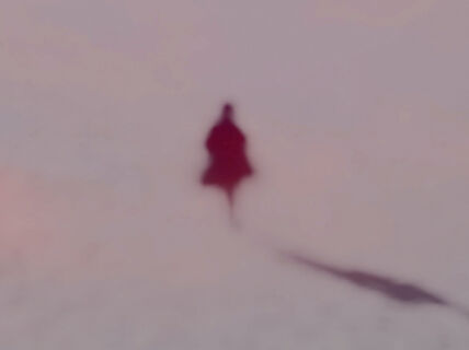 Utuinen ihmishahmo näyttää kävelevän pois päin, varjo heijastuu vaalealle pinnalle 