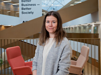 Kuvassa saara Hietanen seisoo Kauppakorkeakoulun aulassa portaiden edessä. 