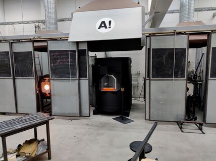 A photograph of the glass melting furnaces emitting orange hot heat which reflects the extreme temperatures of the glass melting process.