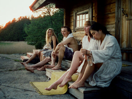 People sitting in front of a cottage after a sauna 