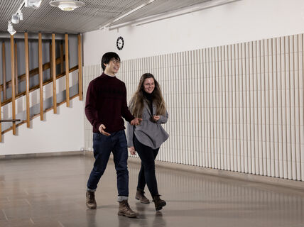 Kaksi ihmistä kävelee käytävällä ja puhuu keskenään.