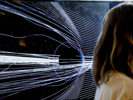 On the background, white radiant lines over a black bacground and only hair and shoulder of a person passing by visible