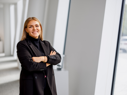 A woman wearing black jacket is smiling and standing in a white isle