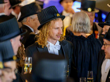 A man with a doctor's hat on celebrating his promotion as a doctor with other doctors