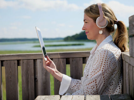 Nainen opiskelemassa kuulokkeet korvilla