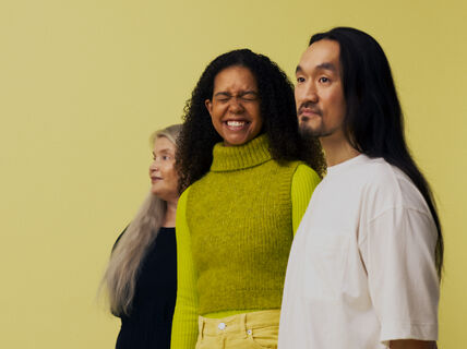 Three people are standing next to each other.