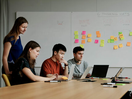 Team of 4 people looking at two computers