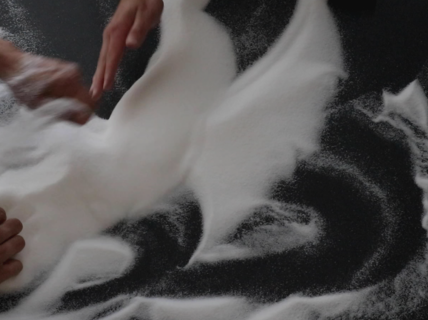 Hands moving salt around on a black background