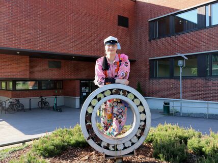 Rasmus Mäkinen poseeraa haalareissa ja ylioppilaslakissa Otaniemen kampuksella.