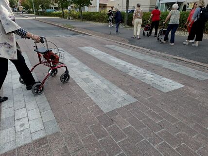 A person crossing a street with a rollator