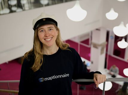 Emily Johnson in Learning Centre wearing student cap and her company's college shirt.