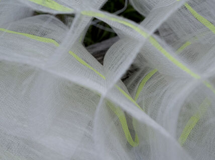 Close-up of white mulkti-layer woven fabric with neon yellow stripes, creating a wavy pattern.