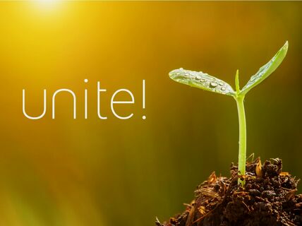 A young green seedling with water droplets in soil. 'unite!' text is written on the yellow-orange background.