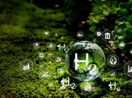 A glass ball with H2 symbol on green vegetation, surrounded by various eco and science icons.