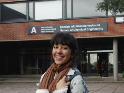 Individual holding a cup stands in front of Aalto University School of Chemical Engineering building.
