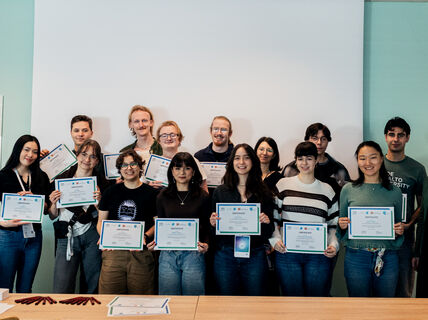 A group of people holding certificates, standing indoors in front of a whiteboard.