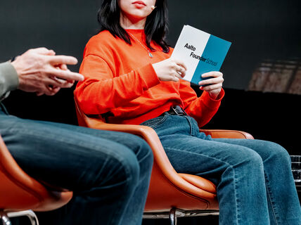 Girl holding a white and blue card that says "Aalto Founder School"