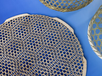 Round beige honeycomb-pattern mat with wicker baskets on bright blue background