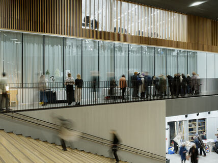 Blurred people walking on indoor stairs and balcony in a modern glass and wood building