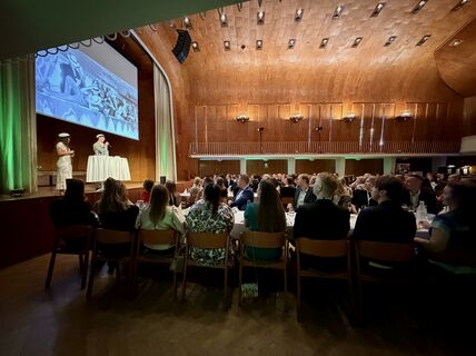 On the stage, KY Chair of the Board Vilma Paavola and alumni representative Tatu Lehtisyrjä, in the crowd class representatives sitting at the tables.