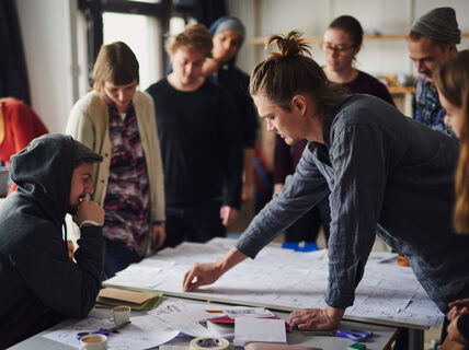 Group of young adults around a table, co-creating with sticky notes in a bright studio