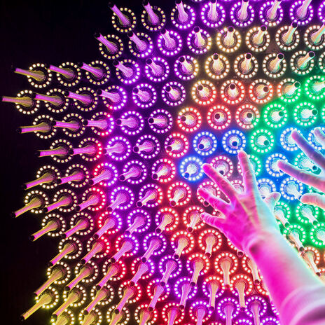Hands reaching towards different cooured lights in Aalto University Science Lab