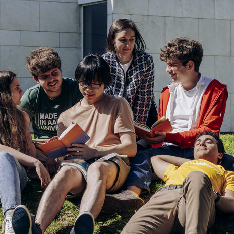 Students hanging out outside on the lawn at university campus