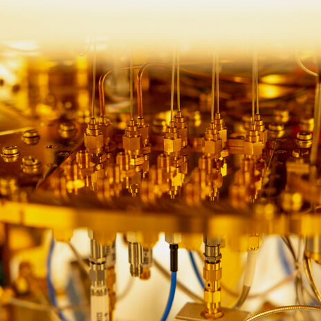 Lähikuva monimutkaisesta kultaisen värisestä koneesta, jossa on erilaisia johtoja ja liittimiä.