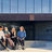 Four students sitting in on a wall outside the Aalto University School of Business building. They are all laughing and discussing vividly.