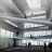 Thumbnail of Modern building interior with multiple floors, large windows, and people walking on ramps.