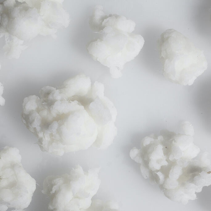 Several white cellulose fibre balls resembling cotton balls on a white surface.