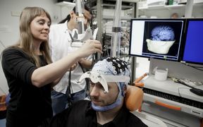 Researcher setting braing imaging receptors to a voluntary subject