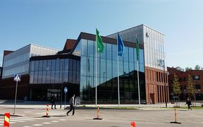 Outside picture of the School of Business building in Otaniemi. Three Aalto Flags swinging in front of the building.