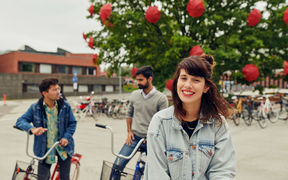 Three students with bicycles in front of Väre building, Aalto University
