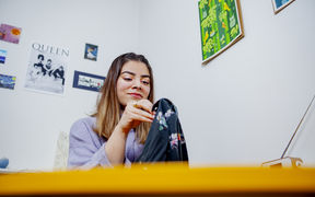 Marium Durrani ompelemassa käsin vaatekappaletta, jossa on kukkakuosi.