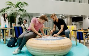 Students sitting by an interesting wooden table doing a puzzle