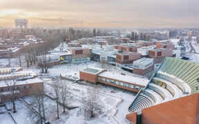 Drone image of Otaniemi campus in early December, light covering of snow everywhere, with low sun shining