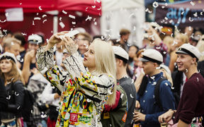 Students celebrating Aalto Day One outside in overalls, with confetti flying.