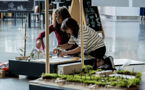 Kaksi opiskelijaa työskentelemässä maisemapienoismallin parissa.