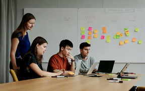 Neljän hengen tiimi katsoo kahta tietokoneruutua