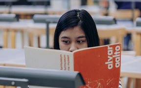 Opiskelija Aallossa lukemassa kirjaa