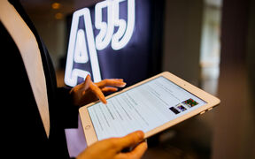 Person som använder en surfplatta bredvid en neonskylt med citattecken.